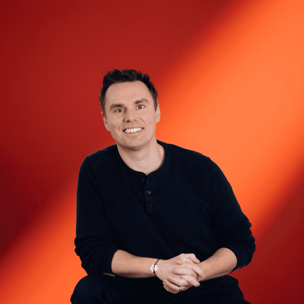 A coach smiling against a warm studio backdrop